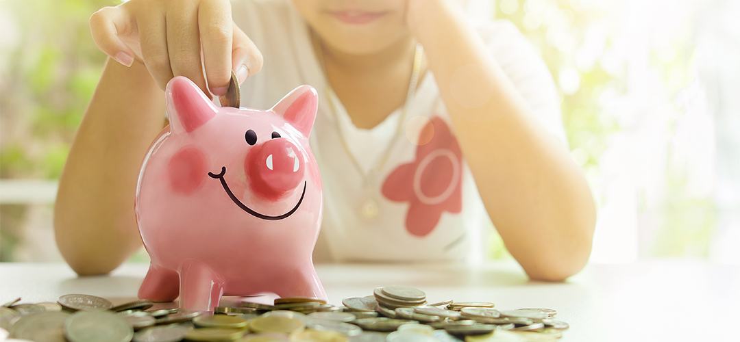 kid putting coin in piggy bank