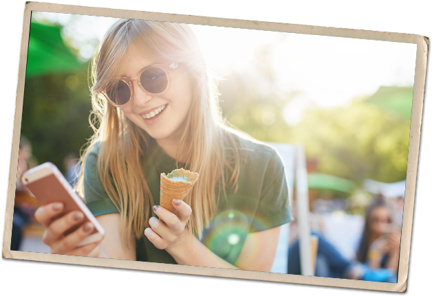 A young woman holding a mobile phone and ice cream cone