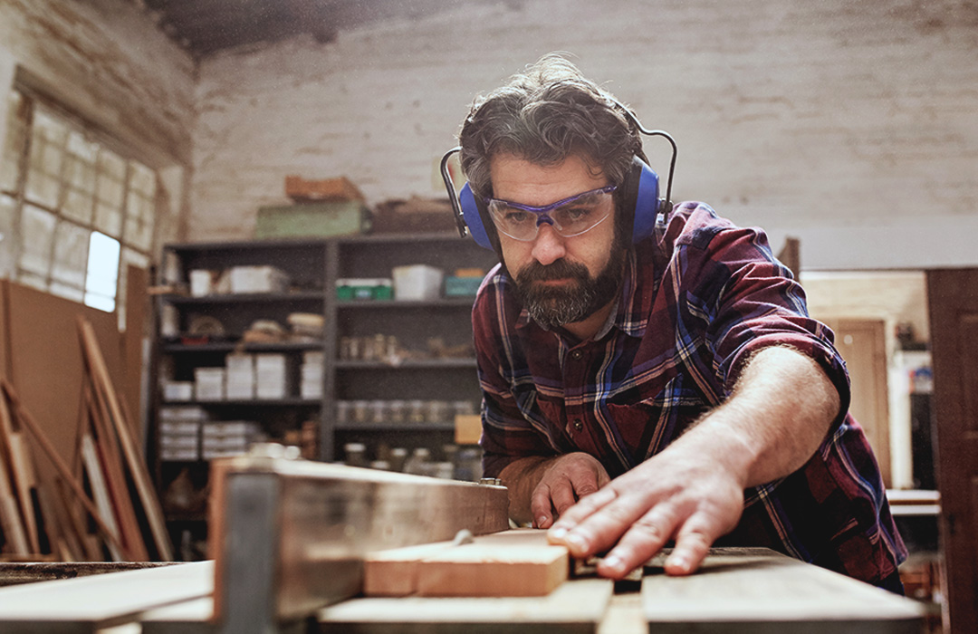 A man works in a woodshop with a saw